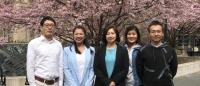 Five people stand in front of blossoming cherry tree on campus